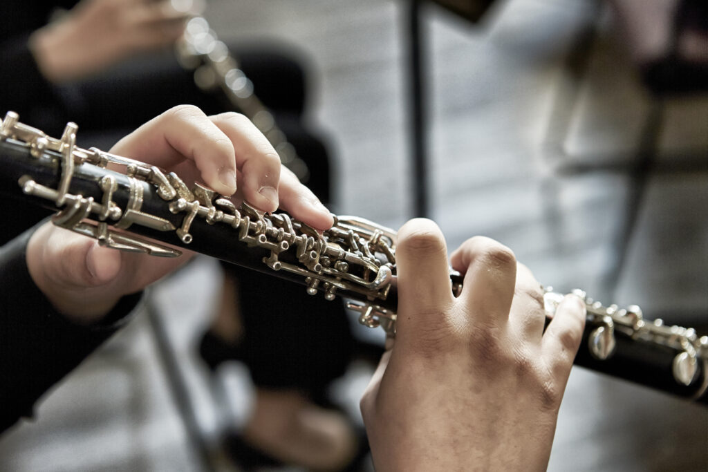 A closeup of a person playing the oboe, indoors